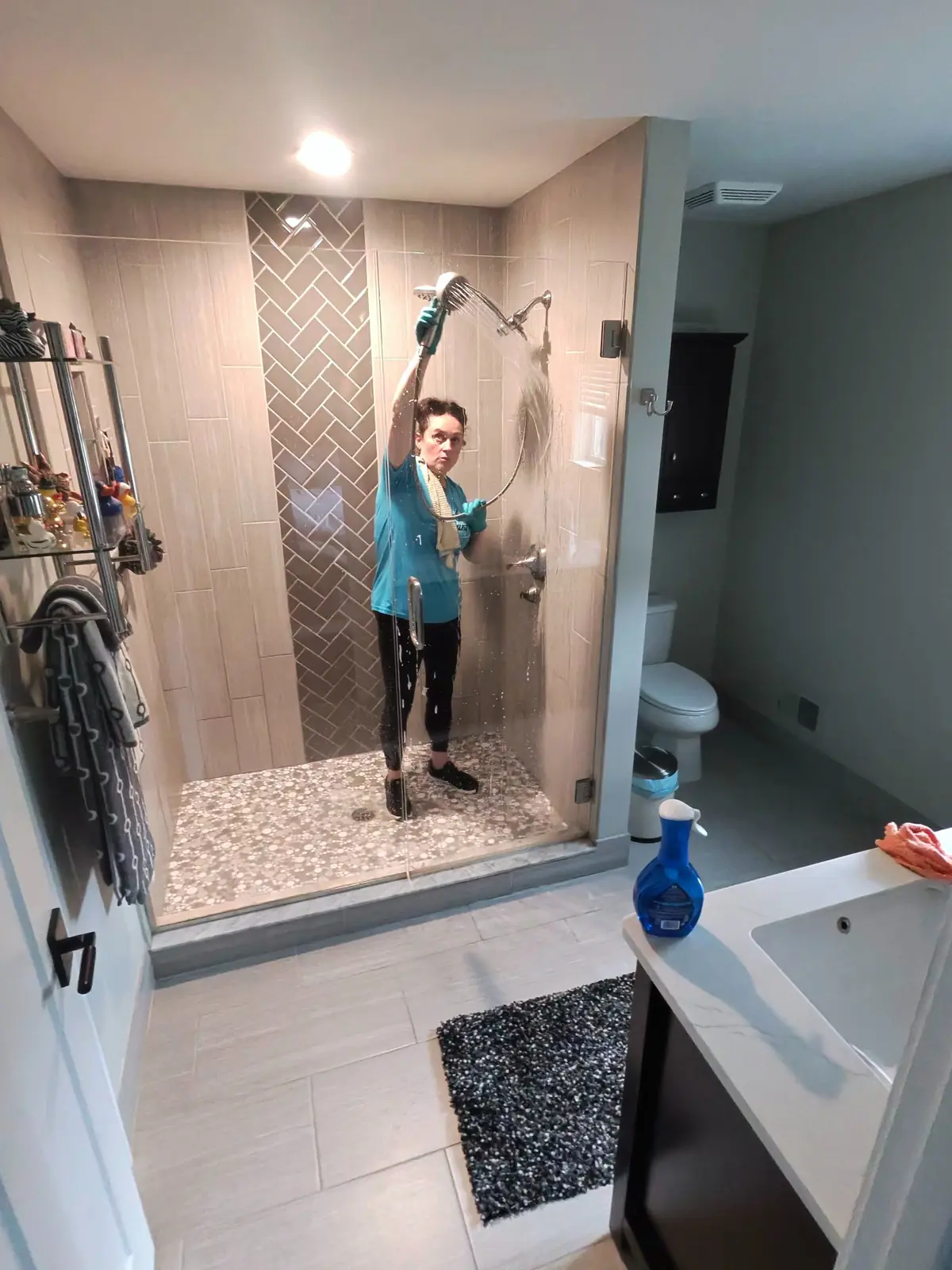 Kellie Erwin rinsing and detailing a glass shower during a deep cleaning visit