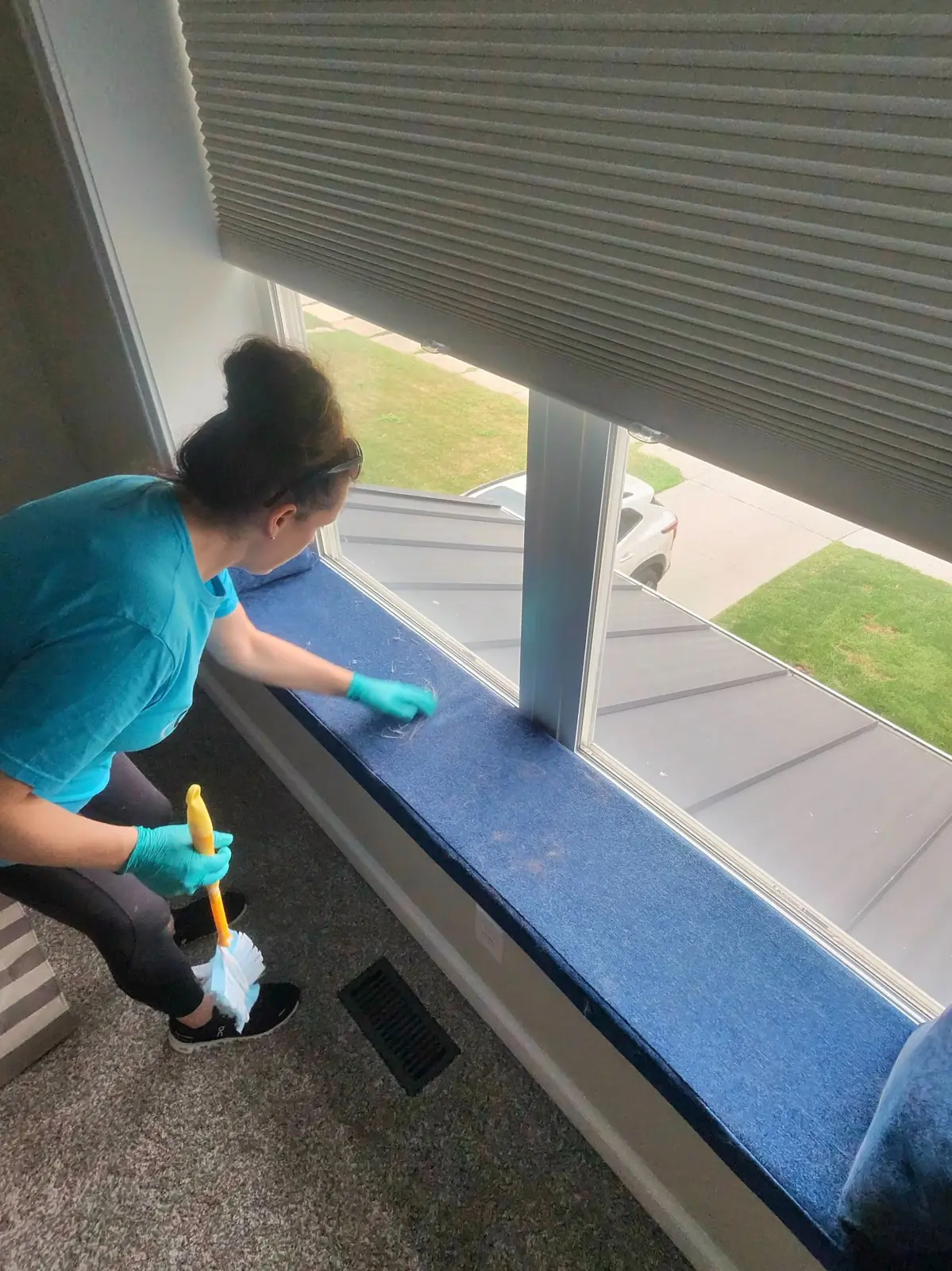 Kellie Erwin hand-cleaning a window ledge during a residential cleaning visit