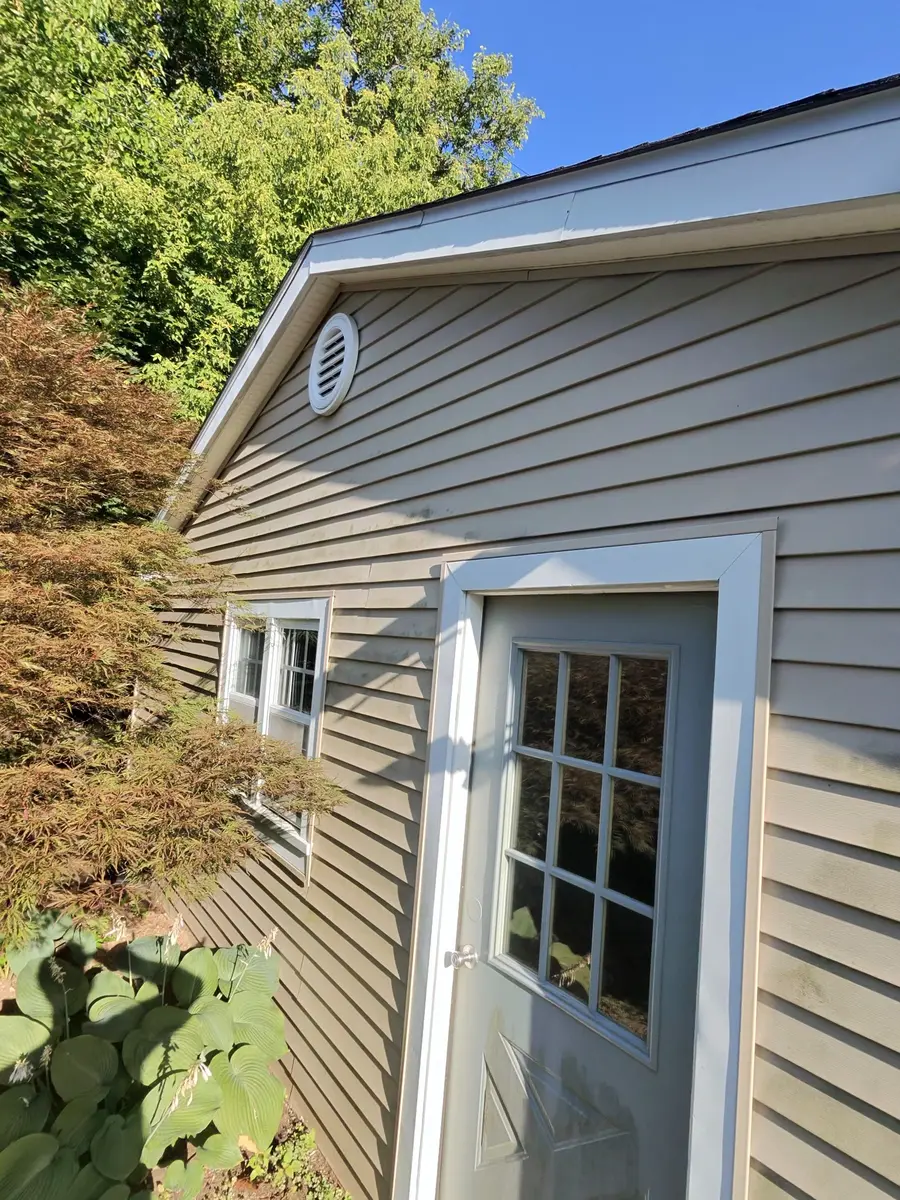 Vinyl siding with organic buildup before Sparkle Team soft washing